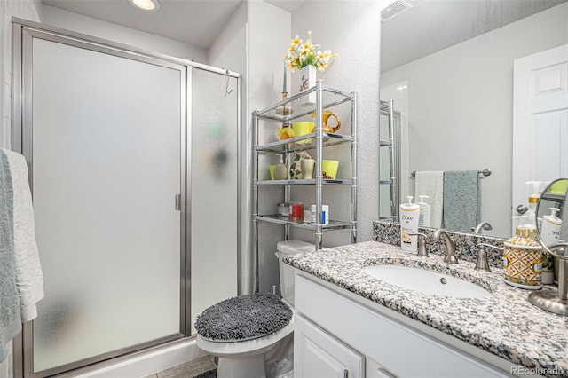 full bath featuring vanity, a shower stall, toilet, and visible vents