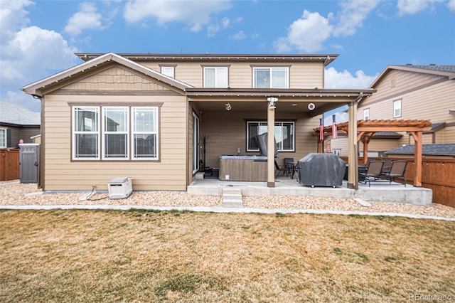 rear view of property featuring a lawn, a pergola, a hot tub, fence, and a patio area