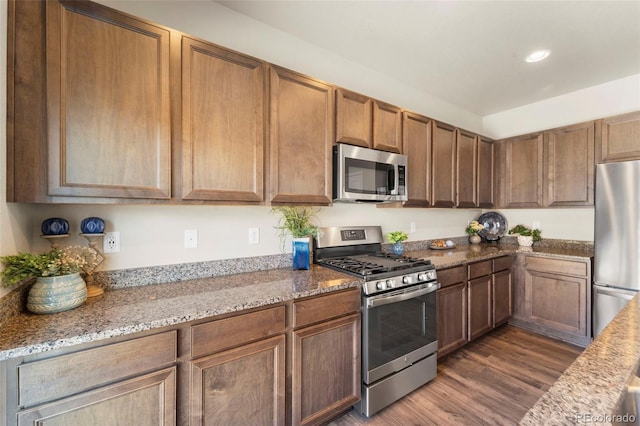 19131 E 65th Ave, Denver, CO 80249 - kitchen featuring stainless steel appliances, dark wood-type flooring, light stone counters, recessed lighting, and brown cabinets