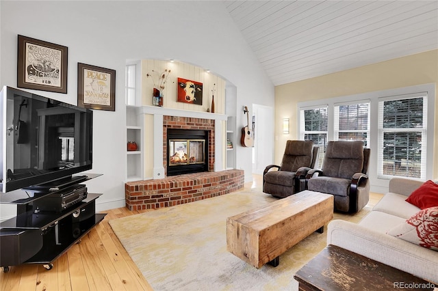 living area with arched walkways, high vaulted ceiling, built in shelves, hardwood / wood-style flooring, and a fireplace