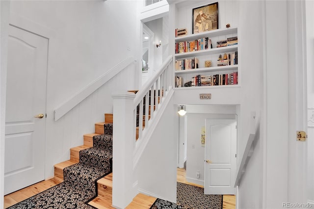 stairway with wood finished floors, visible vents, and a decorative wall