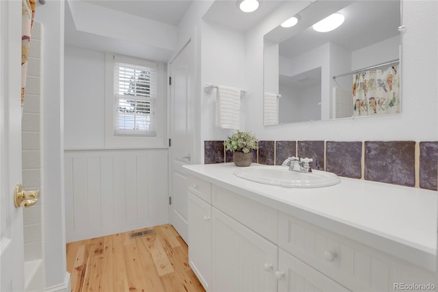 full bathroom with a wainscoted wall, curtained shower, visible vents, vanity, and wood finished floors