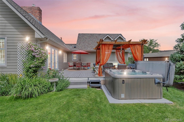 exterior space featuring roof with shingles, a lawn, a hot tub, outdoor dining space, and a deck