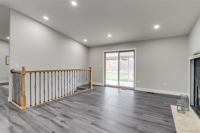 unfurnished living room featuring wood finished floors, visible vents, recessed lighting, baseboards, and a fireplace with flush hearth