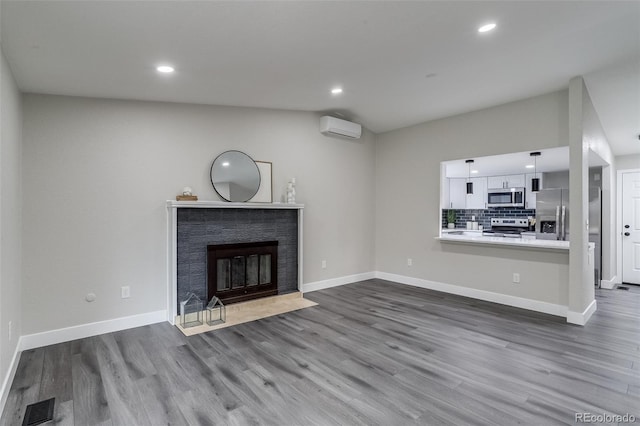 unfurnished living room featuring dark wood-style flooring, a wall mounted AC, a fireplace with flush hearth, and visible vents
