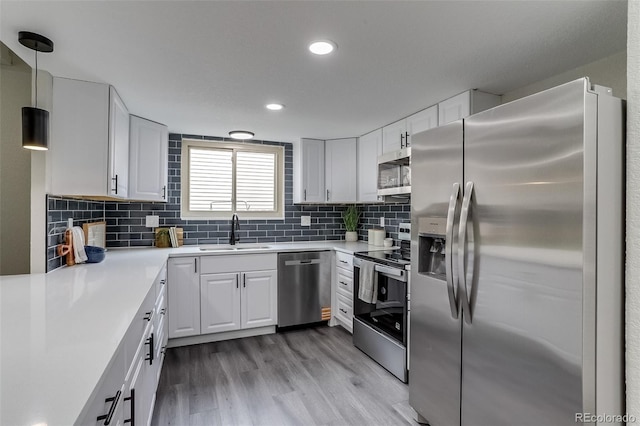 kitchen with light countertops, stainless steel appliances, light wood-style flooring, and a sink