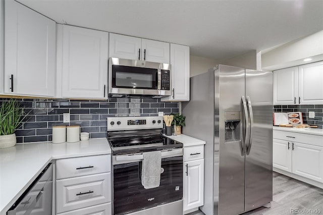 kitchen with white cabinetry, stainless steel appliances, backsplash, and light countertops