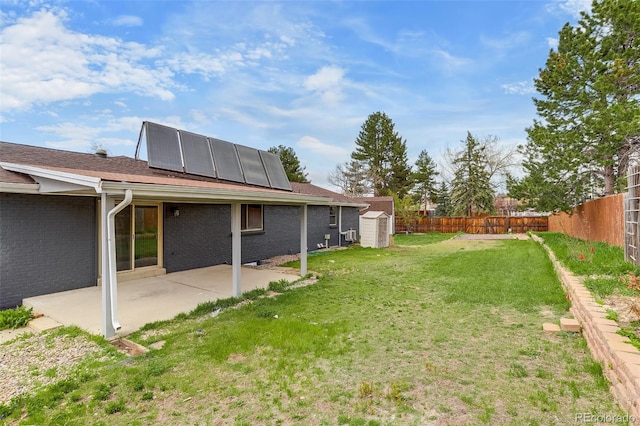 view of yard featuring a patio area, an outdoor structure, a fenced backyard, and a storage unit