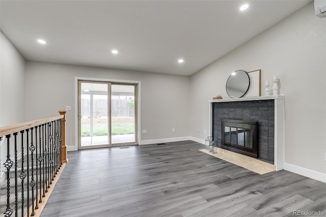 unfurnished living room with wood finished floors, baseboards, a fireplace with flush hearth, and recessed lighting