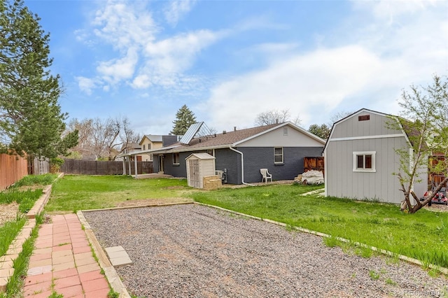 rear view of property featuring a storage shed, a yard, an outdoor structure, a fenced backyard, and brick siding