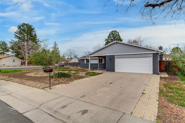 ranch-style house featuring driveway, brick siding, an attached garage, and fence