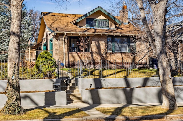 view of front of home with a fenced front yard, a chimney, and brick siding