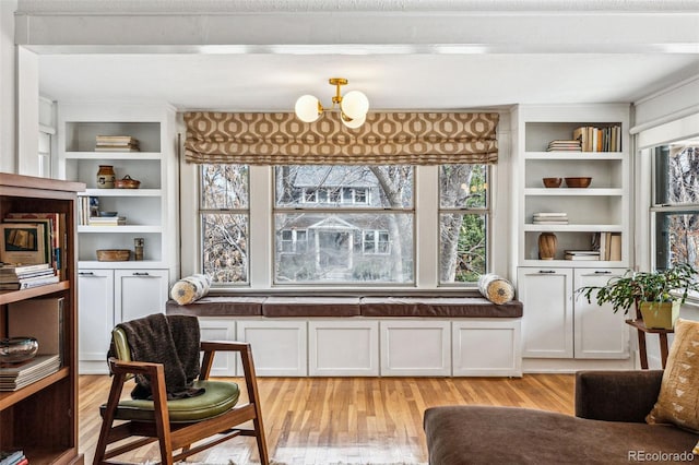 sitting room with light wood-style floors, built in shelves, and a chandelier