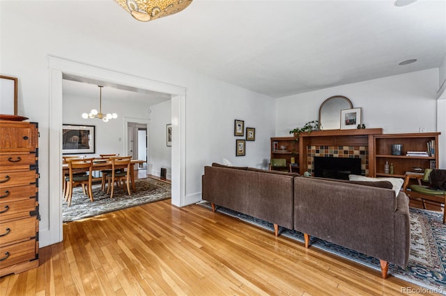 living area featuring light wood finished floors, a fireplace, and an inviting chandelier