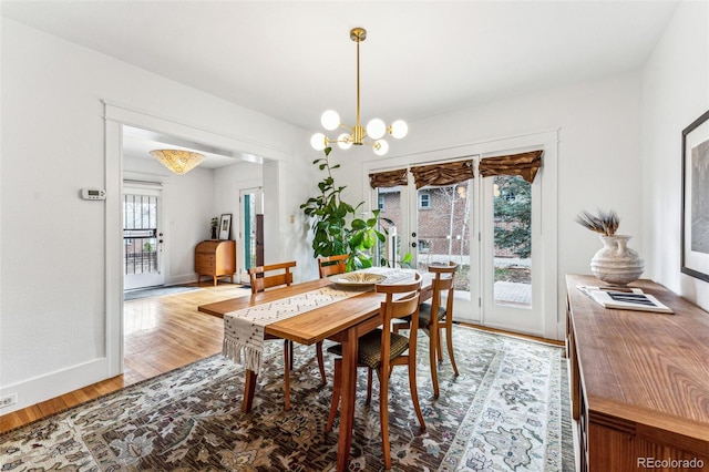 dining area featuring light wood-type flooring, french doors, baseboards, and an inviting chandelier