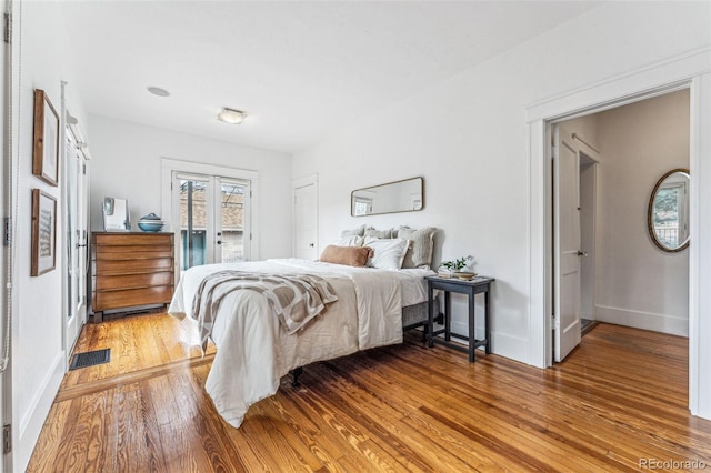 bedroom featuring access to outside, visible vents, light wood-style flooring, and baseboards