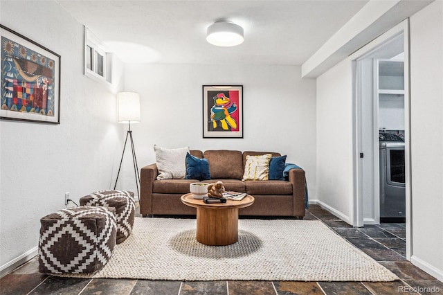 living room with stone tile floors, washer / clothes dryer, and baseboards