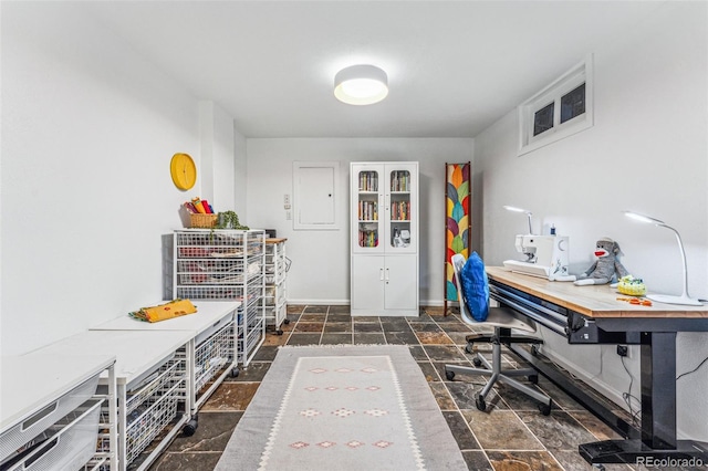 office space featuring stone finish flooring, electric panel, and baseboards