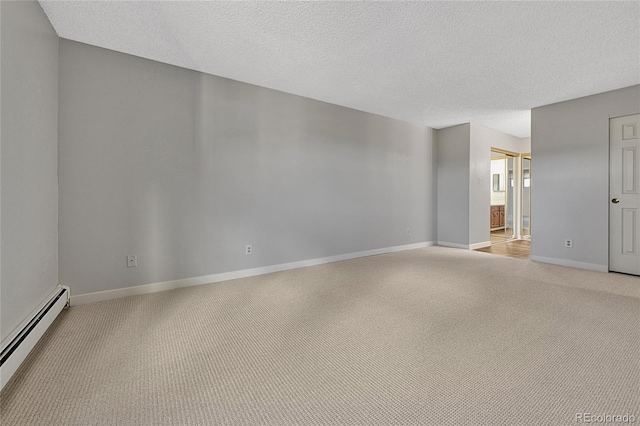 empty room featuring a baseboard heating unit, baseboards, light colored carpet, and a textured ceiling