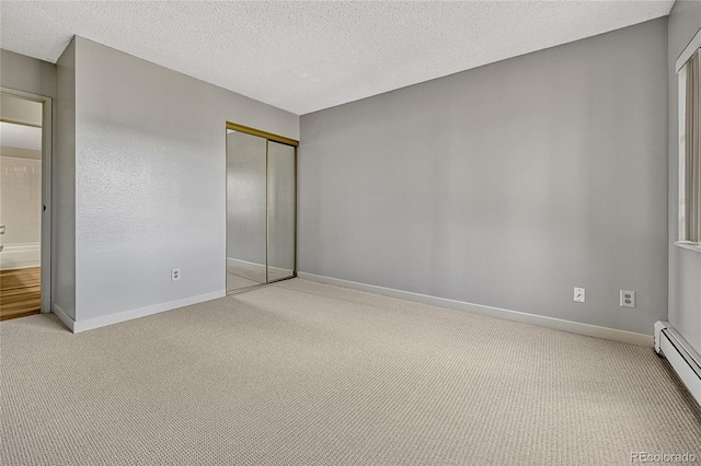 unfurnished bedroom with a textured ceiling, a closet, baseboard heating, and light carpet