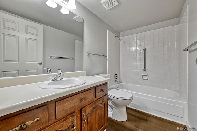 bathroom with visible vents, toilet, vanity, wood finished floors, and washtub / shower combination