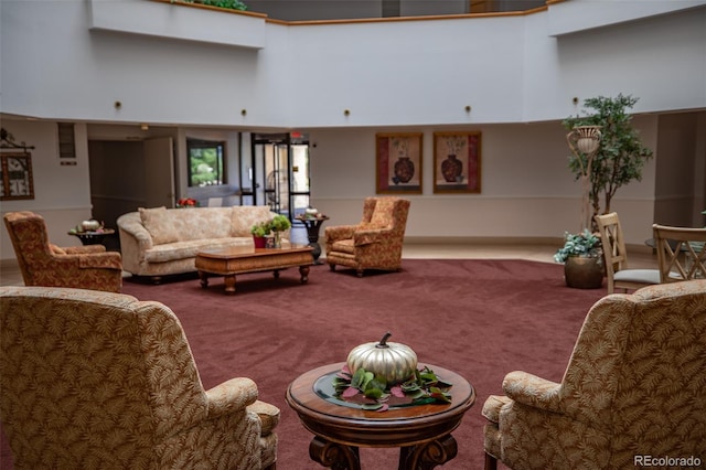 living area featuring a high ceiling and carpet