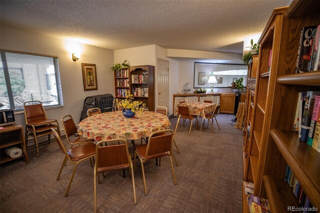 dining space featuring a textured ceiling, a baseboard heating unit, and dark colored carpet