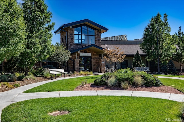 contemporary home featuring stone siding and a front lawn