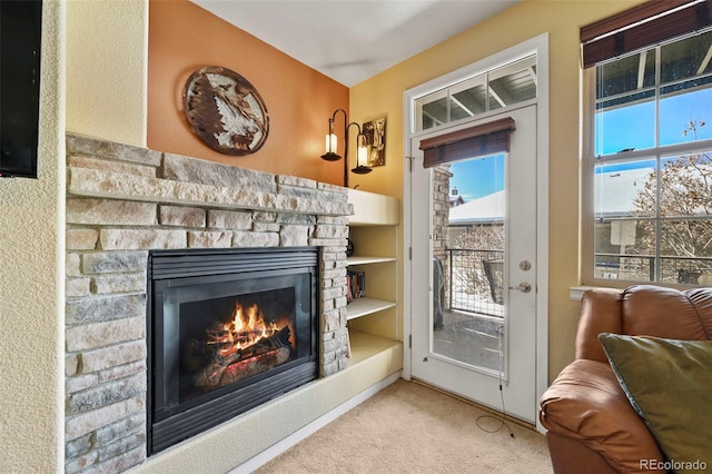 entryway with light carpet, built in shelves, a wealth of natural light, and a fireplace