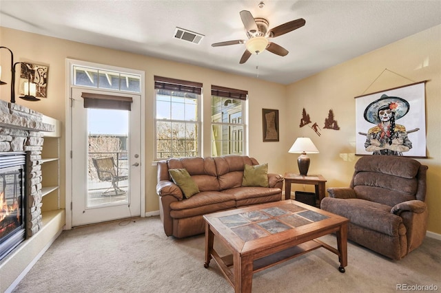 carpeted living room with ceiling fan and a fireplace