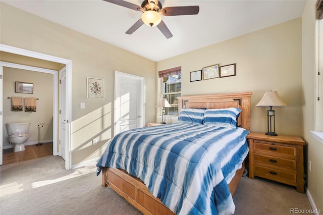 carpeted bedroom with ensuite bath and ceiling fan