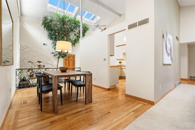 dining area featuring high vaulted ceiling, a ceiling fan, light wood finished floors, and visible vents