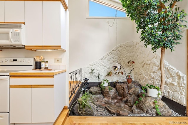 kitchen featuring white appliances, white cabinetry, and light countertops