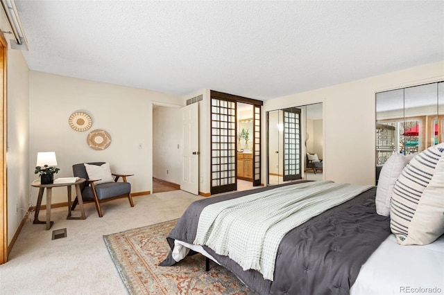 carpeted bedroom with two closets, a textured ceiling, visible vents, and baseboards