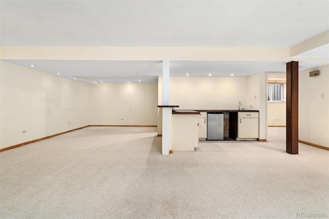 finished below grade area featuring light colored carpet, a sink, recessed lighting, wet bar, and baseboards