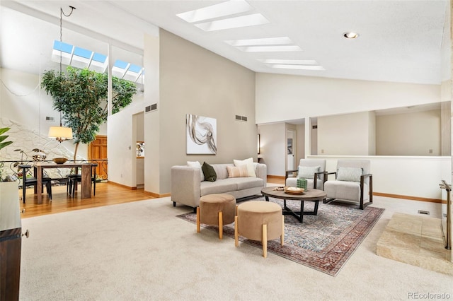 living area featuring a skylight, visible vents, carpet, and high vaulted ceiling