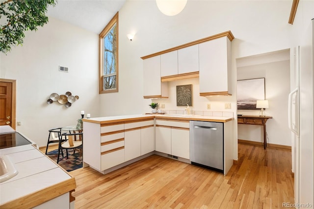 kitchen featuring stainless steel dishwasher, visible vents, light wood-style floors, high vaulted ceiling, and white cabinetry