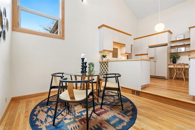 dining space with high vaulted ceiling, visible vents, baseboards, and light wood finished floors