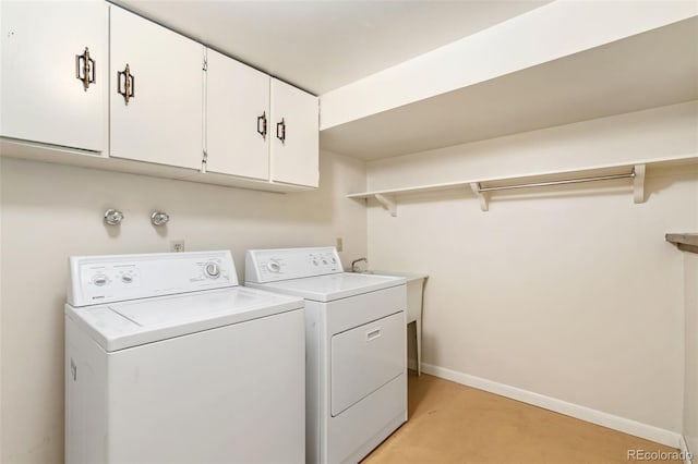 washroom featuring washing machine and clothes dryer, baseboards, and cabinet space
