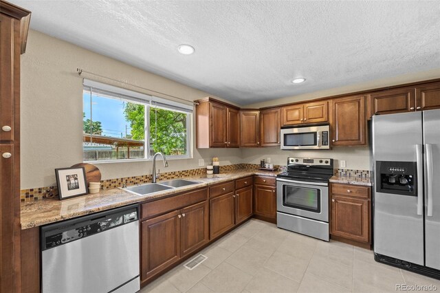 2380 W Baltic Pl, Englewood, CO 80110 - kitchen featuring stainless steel appliances, a textured ceiling, recessed lighting, light stone countertops, and light tile patterned floors