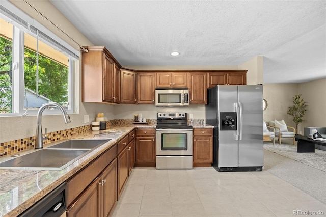 2380 W Baltic Pl, Englewood, CO 80110 - kitchen with appliances with stainless steel finishes, brown cabinets, recessed lighting, a textured ceiling, and decorative backsplash