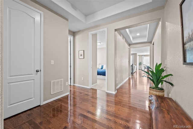 827 Sundance Ln, Erie, CO 80516 - hallway with a raised ceiling, wood finished floors, visible vents, a textured wall, and baseboards