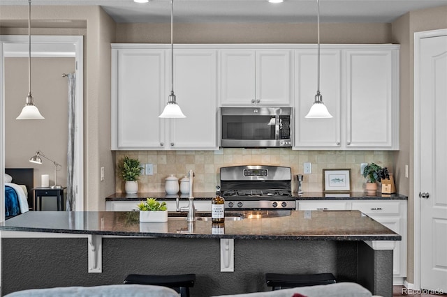 827 Sundance Ln, Erie, CO 80516 - kitchen featuring backsplash, white cabinetry, a kitchen breakfast bar, and stainless steel appliances