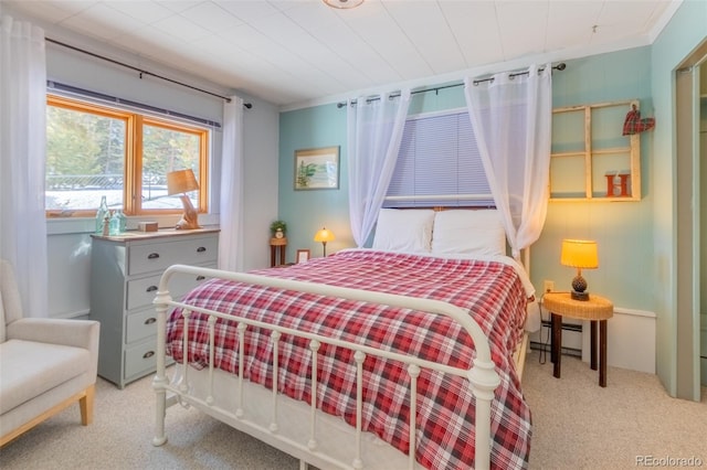 bedroom with a baseboard heating unit and light carpet