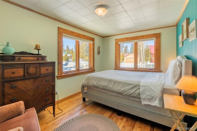 bedroom featuring light wood-style floors, baseboards, and ornamental molding