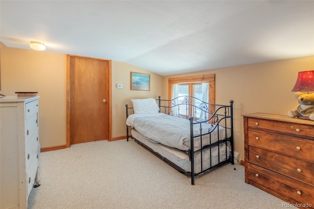 bedroom featuring lofted ceiling, light carpet, and baseboards