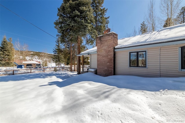 snow covered property with a chimney