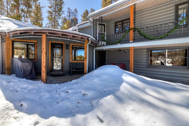 snow covered property entrance with a balcony