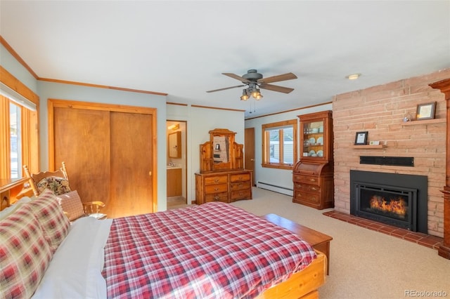 bedroom featuring light carpet, ornamental molding, a fireplace, a baseboard heating unit, and a closet