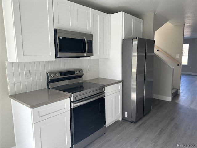 kitchen featuring appliances with stainless steel finishes, light wood-type flooring, white cabinets, and tasteful backsplash